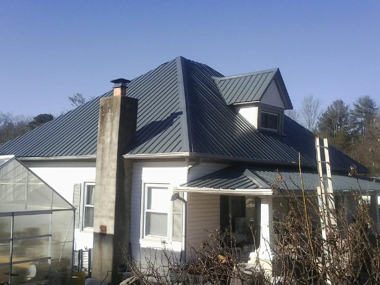 Dark blue standing seam metal roof on a white farmhouse with dormer — Slate & Tile Roof Repair by Roofing Brothers in Glen Saint Mary