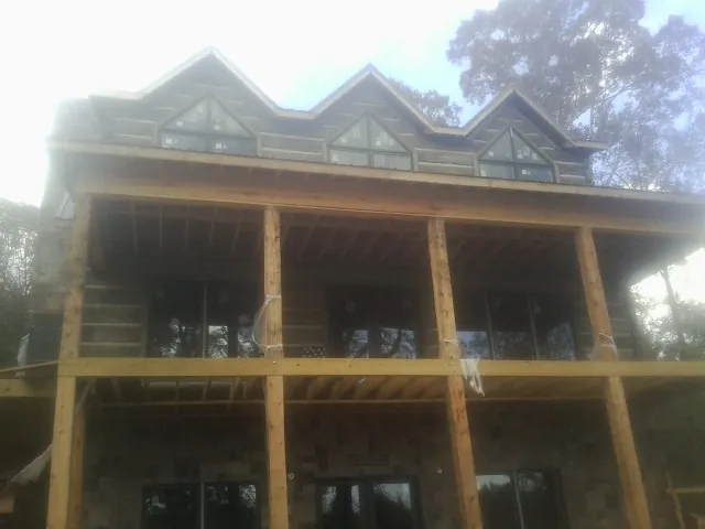 Dormers and porch framing on a large log home under construction — Roof Coating work by our crew in Glen Saint Mary