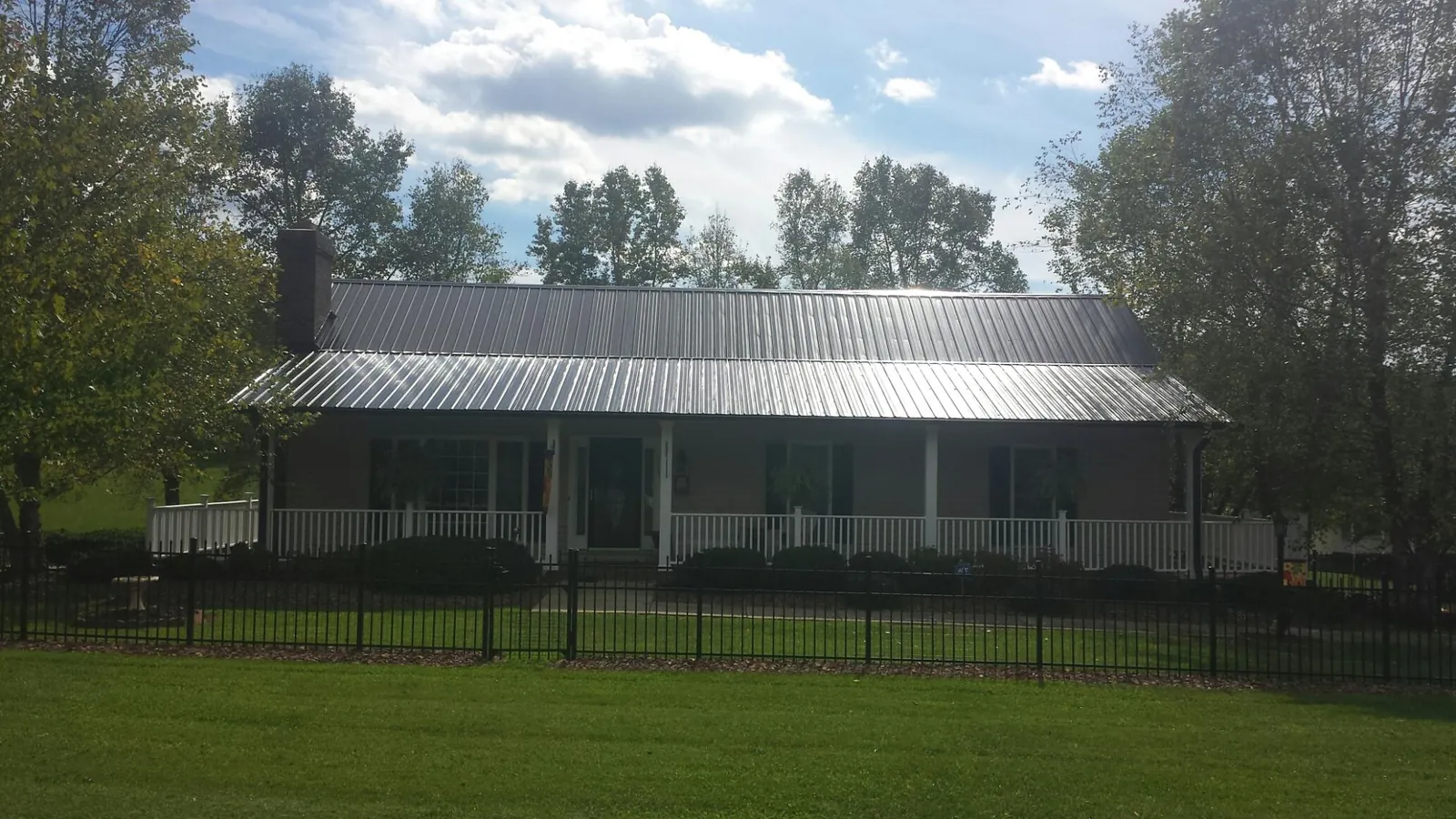 Gray metal roof on a brick ranch with a full width front porch — Gutter Guard Installation work by our crew in Glen Saint Mary