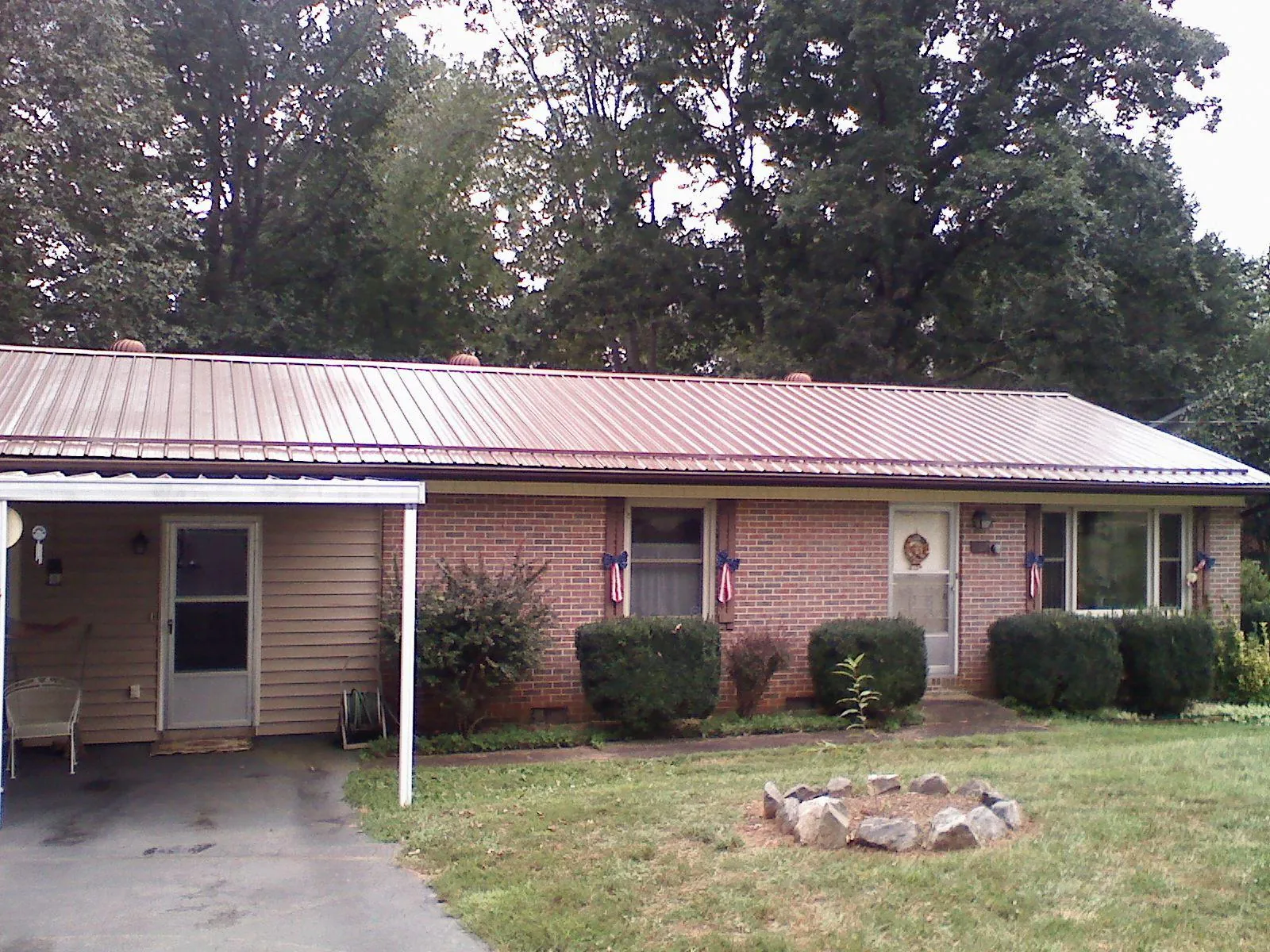 Bronze metal roof and carport on a brick ranch home — Roof Repair work by our crew in Glen Saint Mary