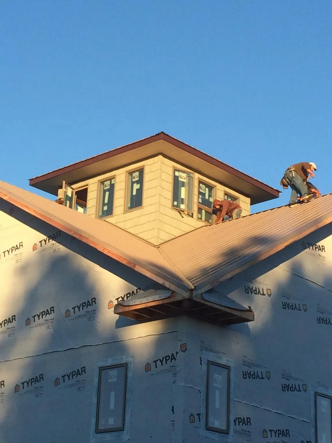 Roofers working around a rooftop cupola on a new metal roof at sunset — Roof Waterproofing in Glen Saint Mary by Roofing Brothers